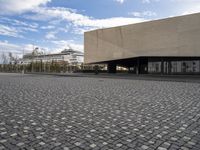 an empty building with a large sidewalk and cobbles on it's side of the street