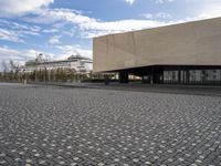 an empty building with a large sidewalk and cobbles on it's side of the street