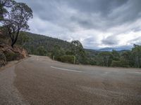 a person riding a motorcycle down a road on top of a hill with a cloudy sky