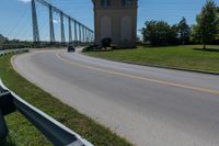 the roadway has the road going up to the bridge and has some large poles over it