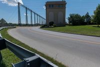 the roadway has the road going up to the bridge and has some large poles over it