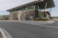 a building with many windows and some grass on the sidewalk in front of it is empty