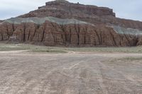 an empty field next to a big mountain with rocks in the background of the picture