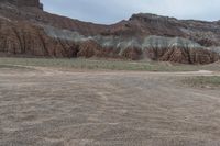 an empty field next to a big mountain with rocks in the background of the picture