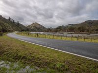 a long road winding through the middle of a mountain valley on an overcast day