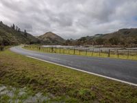 a long road winding through the middle of a mountain valley on an overcast day