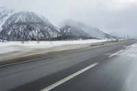 a freeway near some mountains and trees during the snow in wintertime in a blurry effect