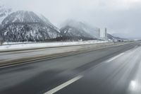 a freeway near some mountains and trees during the snow in wintertime in a blurry effect