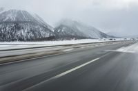 a freeway near some mountains and trees during the snow in wintertime in a blurry effect