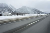 a freeway near some mountains and trees during the snow in wintertime in a blurry effect