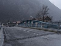 the bridge is empty during the rainy day on the mountainside road below, and houses in the background