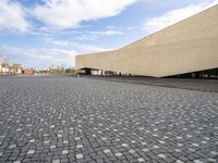 an empty courtyard is shown in this picture with a building that has many windows and some buildings