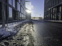 the sun is shining on the road in the city in winter time by a glass building