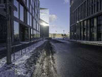 the sun is shining on the road in the city in winter time by a glass building