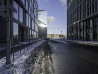 the sun is shining on the road in the city in winter time by a glass building