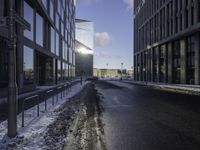 the sun is shining on the road in the city in winter time by a glass building