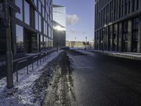 the sun is shining on the road in the city in winter time by a glass building