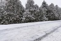 a snowy road surrounded by snow and evergreen trees with lots of snow on it's side