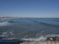 surfers are in the ocean waiting for waves to break on their stomachs as they head towards shore