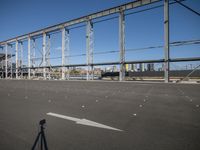 a empty parking lot with a long metal bridge in the background and a light on the ground