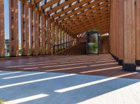 the walkway inside the building has a wooden structure, large windows, and a metal gate