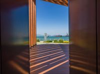 open doors on a walkway overlooking an ocean with buildings in the distance and blue skies