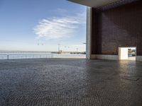 a room with bricks, an open door, and a body of water below the walls