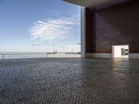 a room with bricks, an open door, and a body of water below the walls