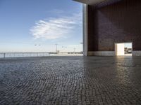 a room with bricks, an open door, and a body of water below the walls