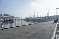 walkway on pier with boats in the harbor and buildings in the background to the right
