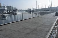 walkway on pier with boats in the harbor and buildings in the background to the right