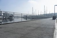 walkway on pier with boats in the harbor and buildings in the background to the right