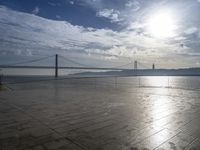 the sun shines brightly across a bridge and body of water at the top of it