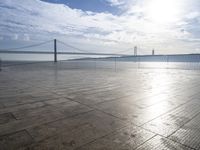 the sun shines brightly across a bridge and body of water at the top of it