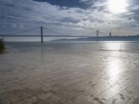 the sun shines brightly across a bridge and body of water at the top of it