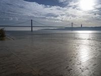 the sun shines brightly across a bridge and body of water at the top of it