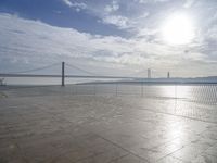 the sun shines brightly across a bridge and body of water at the top of it