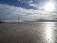 the sun shines brightly across a bridge and body of water at the top of it