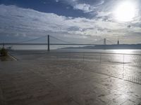 the sun shines brightly across a bridge and body of water at the top of it