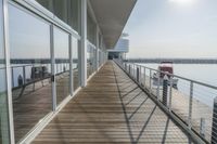 an empty pier with a bench at the end of it and an ocean view through glass