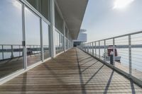 an empty pier with a bench at the end of it and an ocean view through glass