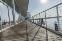 an empty pier with a bench at the end of it and an ocean view through glass