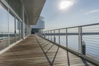 an empty pier with a bench at the end of it and an ocean view through glass