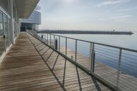 an empty pier with a bench at the end of it and an ocean view through glass