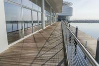 an empty pier with a bench at the end of it and an ocean view through glass