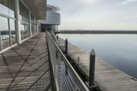 an empty pier with a bench at the end of it and an ocean view through glass