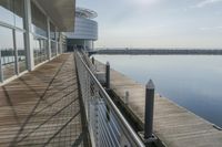 an empty pier with a bench at the end of it and an ocean view through glass