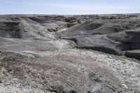 a dirt road is surrounded by some hills and desert like terrain as the vehicle sits on it