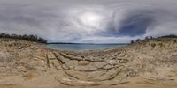 a panoramic view of a beach with cliffs and sea in the background, from a low angle