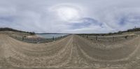 a panoramic view of the beach and fenced off sand area on a cloudy day